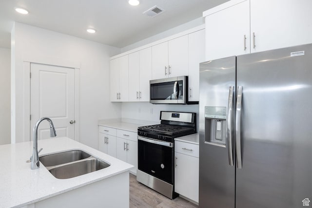 kitchen with light hardwood / wood-style flooring, sink, white cabinetry, light stone counters, and stainless steel appliances