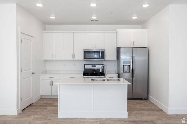 kitchen with sink, white cabinetry, an island with sink, light hardwood / wood-style floors, and stainless steel appliances