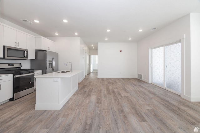 kitchen with sink, white cabinets, a center island with sink, and stainless steel appliances