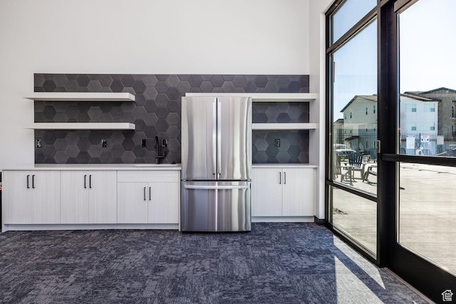 kitchen with backsplash, sink, stainless steel fridge, and white cabinets