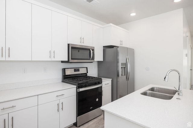 kitchen with sink, white cabinetry, stainless steel appliances, and light wood-type flooring