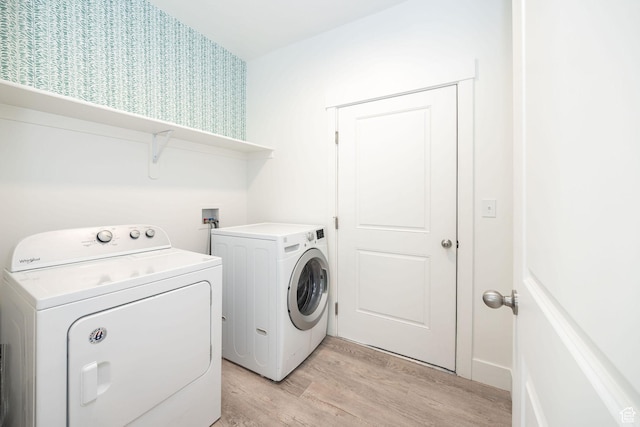 clothes washing area featuring washer and clothes dryer and light hardwood / wood-style flooring