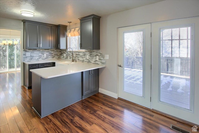 4698 Porter Ave, South Ogden, UT 84403 - kitchen featuring kitchen peninsula, hanging light fixtures, sink, dark wood-type flooring, and decorative backsplash
