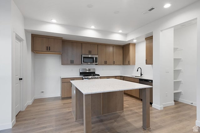 7091 W S Jordan Pkwy Unit 394, South Jordan, UT 84009 - kitchen with appliances with stainless steel finishes, a sink, a center island, tasteful backsplash, and light wood-style flooring