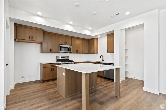 kitchen with appliances with stainless steel finishes, baseboards, decorative backsplash, a kitchen island, and recessed lighting