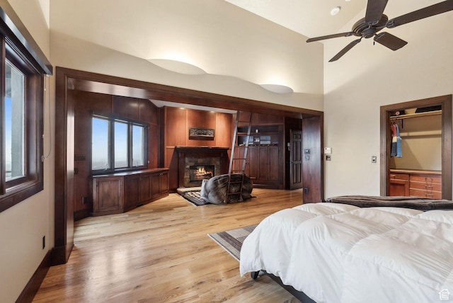 4552 S Zarahemla Dr E, Salt Lake City, UT 84124 - bedroom featuring a warm lit fireplace, baseboards, a towering ceiling, and light wood-style floors