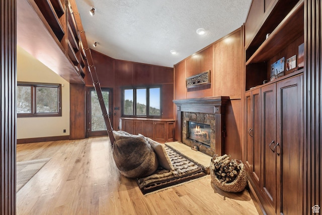 4552 S Zarahemla Dr E, Salt Lake City, UT 84124 - living area featuring baseboards, a stone fireplace, a textured ceiling, light wood-style floors, and lofted ceiling