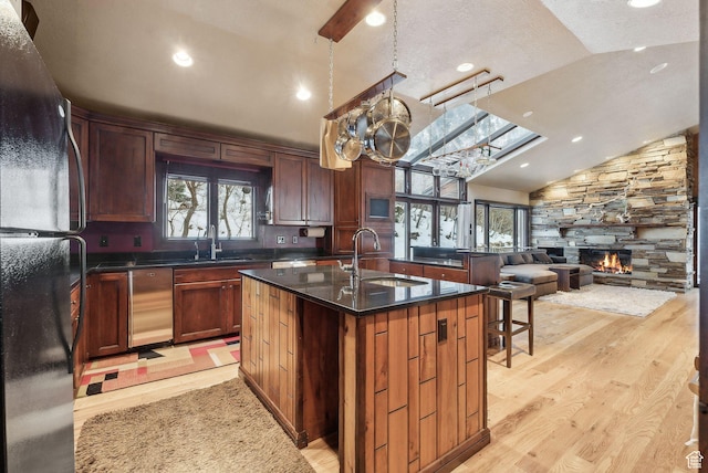 4552 S Zarahemla Dr E, Salt Lake City, UT 84124 - kitchen with freestanding refrigerator, a sink, lofted ceiling, and a fireplace