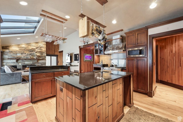 4552 S Zarahemla Dr E, Salt Lake City, UT 84124 - kitchen featuring light wood-style flooring, a kitchen island with sink, stainless steel microwave, open floor plan, and extractor fan