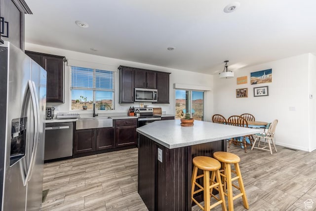 kitchen featuring appliances with stainless steel finishes, sink, a kitchen bar, a kitchen island, and dark brown cabinetry