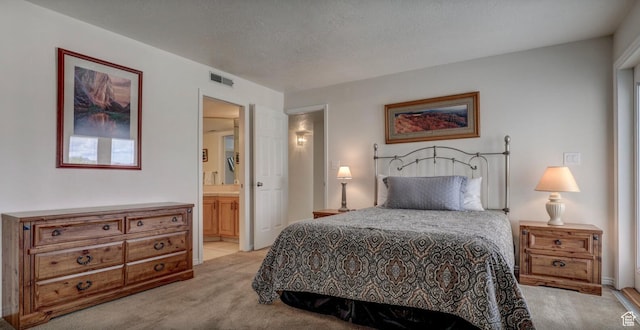 bedroom with light colored carpet, a textured ceiling, and ensuite bathroom