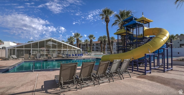 view of swimming pool featuring a patio area, a playground, and a water slide