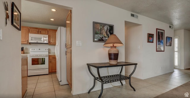 kitchen with light tile patterned flooring, white appliances, and a textured ceiling