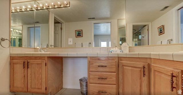 bathroom with a textured ceiling, tile patterned flooring, and vanity