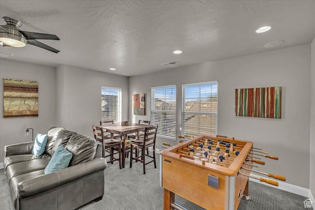 rec room featuring ceiling fan, light colored carpet, and a textured ceiling