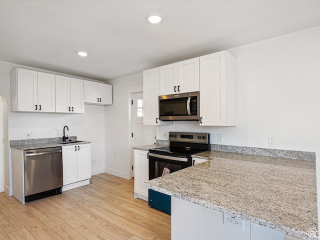 kitchen featuring sink, stainless steel appliances, white cabinets, and light wood-type flooring