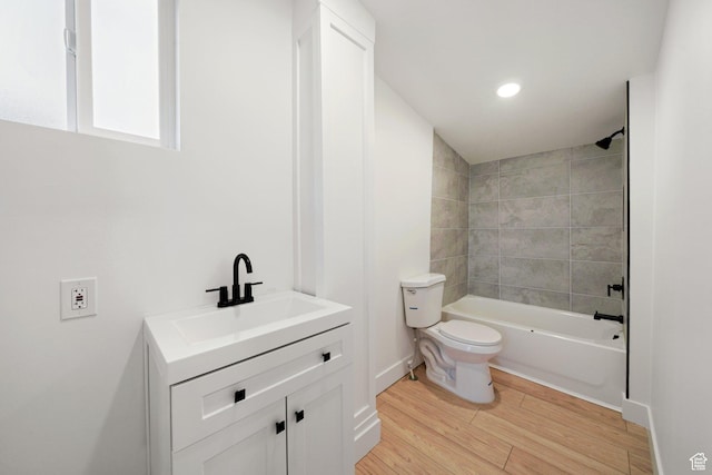 full bathroom featuring tiled shower / bath, vanity, toilet, and hardwood / wood-style floors