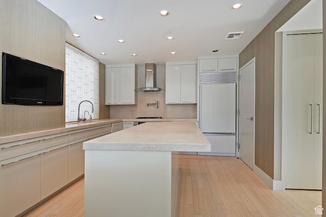 268 S State St E Unit 418, Salt Lake City, UT 84111 - kitchen with built in fridge, white cabinets, a kitchen island, wall chimney range hood, and sink