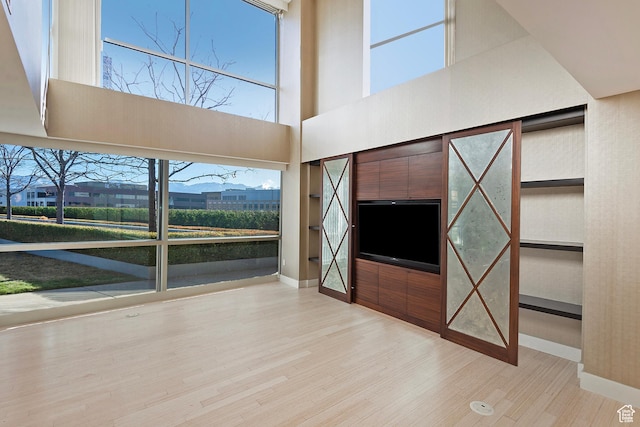 268 S State St E Unit 418, Salt Lake City, UT 84111 - unfurnished living room featuring a towering ceiling and light wood-type flooring