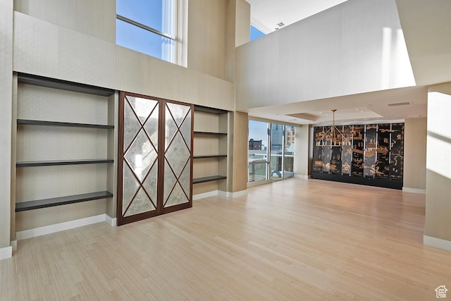 268 S State St E Unit 418, Salt Lake City, UT 84111 - unfurnished living room featuring built in features, a high ceiling, and light hardwood / wood-style flooring