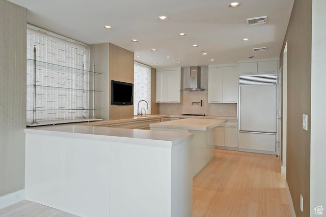268 S State St E Unit 418, Salt Lake City, UT 84111 - kitchen featuring wall chimney range hood, white cabinetry, kitchen peninsula, and paneled built in refrigerator