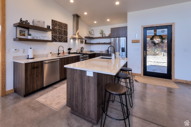 171 E Mt Peale Dr, Moab, UT 84532 - kitchen featuring dark brown cabinetry, wall chimney range hood, stainless steel appliances, sink, and a kitchen island with sink