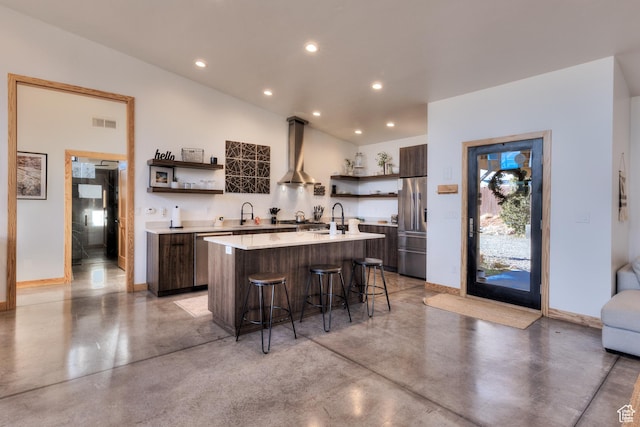 171 E Mt Peale Dr, Moab, UT 84532 - kitchen with appliances with stainless steel finishes, a kitchen breakfast bar, wall chimney range hood, dark brown cabinetry, and an island with sink