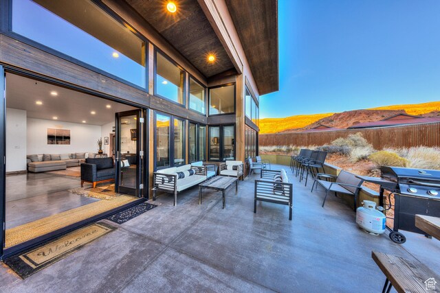patio terrace at dusk featuring a mountain view, outdoor lounge area, and a grill