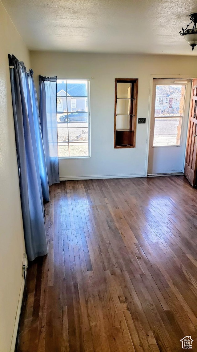 449 E 3rd S, Price, UT 84501 - unfurnished living room with dark wood-type flooring, a textured ceiling, and baseboards
