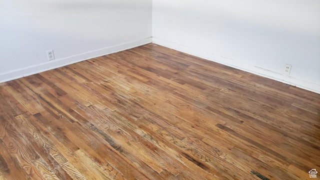 empty room with baseboards and hardwood / wood-style flooring