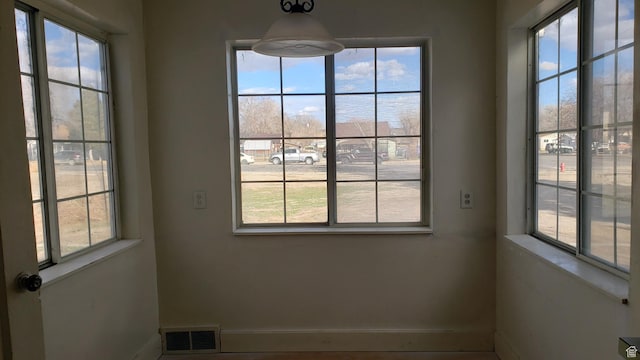 interior space with baseboards, visible vents, and a healthy amount of sunlight