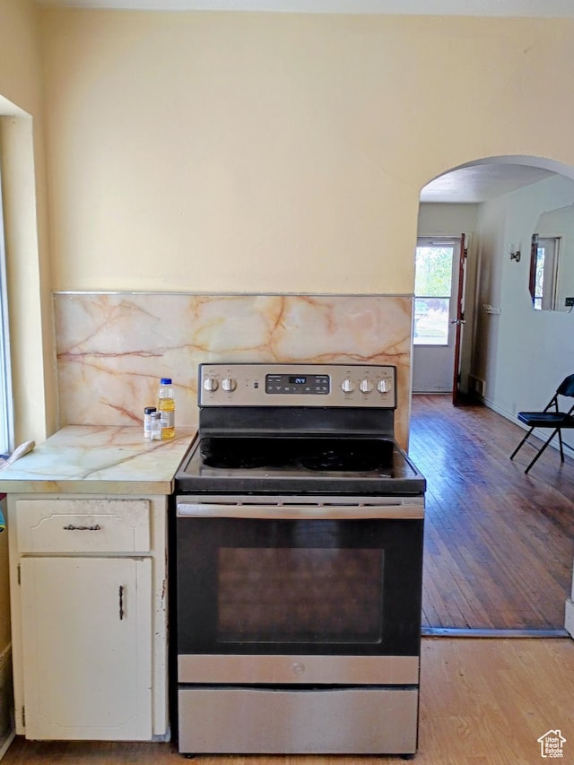 449 E 3rd S, Price, UT 84501 - kitchen with stainless steel electric range oven, arched walkways, white cabinets, light countertops, and light wood-style floors