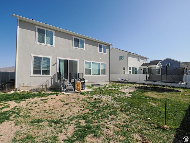 1766 E Johnstown Rd N Unit 710, Eagle Mountain, UT 84005 - back of house featuring a lawn, a fenced backyard, a trampoline, and stucco siding
