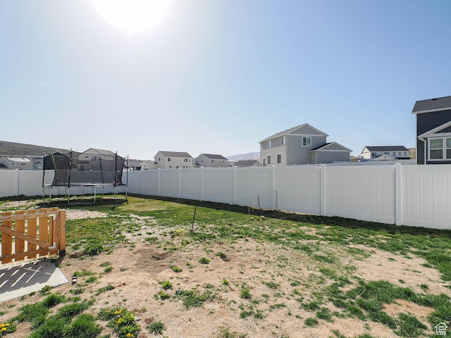 1766 E Johnstown Rd N Unit 710, Eagle Mountain, UT 84005 - view of yard featuring a residential view, a fenced backyard, and a trampoline