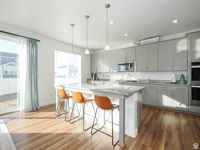 1766 E Johnstown Rd N Unit 710, Eagle Mountain, UT 84005 - kitchen with appliances with stainless steel finishes, gray cabinets, a center island with sink, and wood finished floors