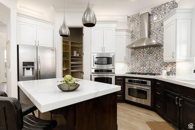 1783 N Firerock Cir, Washington, UT 84780 - kitchen featuring appliances with stainless steel finishes, white cabinets, wall chimney range hood, tasteful backsplash, and a breakfast bar
