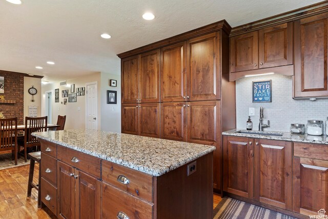 712 S 6150 W, Ogden, UT 84404 - kitchen featuring sink, tasteful backsplash, light stone counters, hardwood / wood-style floors, and a center island