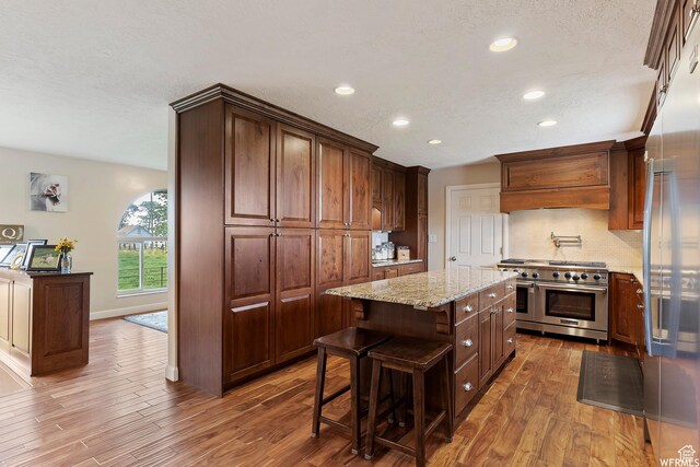 712 S 6150 W, Ogden, UT 84404 - kitchen featuring appliances with stainless steel finishes, a kitchen island, dark wood-type flooring, premium range hood, and backsplash