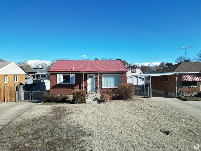 bungalow-style home featuring a gate, concrete driveway, fence, brick siding, and metal roof