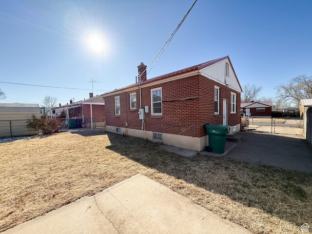 5840 S 2625 W, Roy, UT 84067 - view of property exterior with a chimney, brick siding, fence, and a lawn