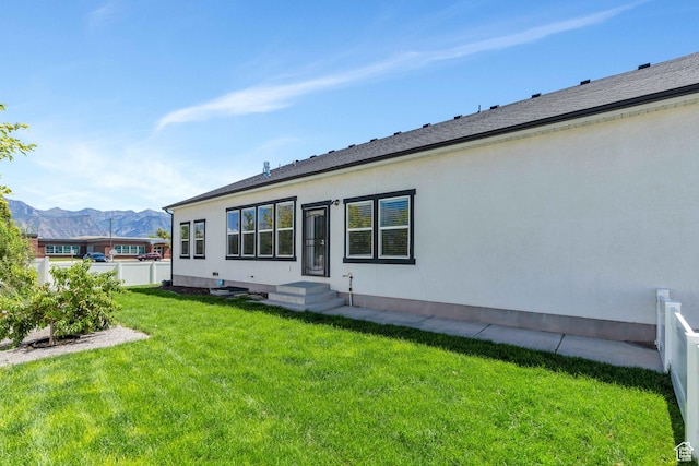 rear view of property with a mountain view and a lawn