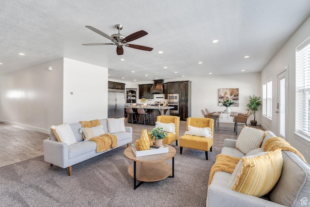 living room with ceiling fan, wood-type flooring, and a textured ceiling