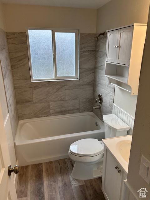 full bathroom featuring hardwood / wood-style flooring, tiled shower / bath, vanity, and toilet