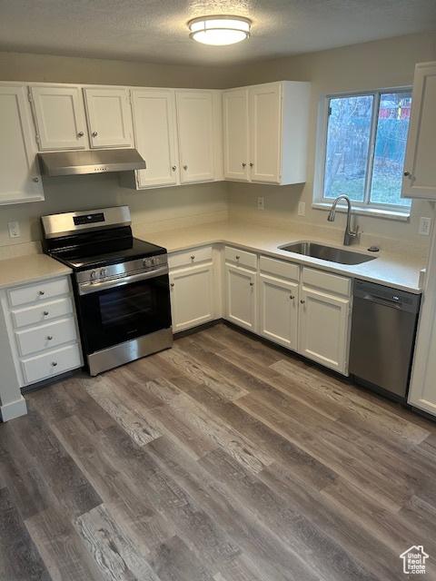 kitchen with sink, stainless steel appliances, dark hardwood / wood-style floors, a textured ceiling, and white cabinets