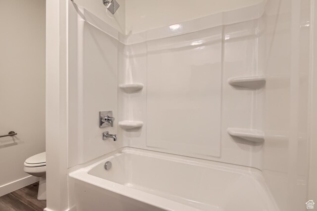 bathroom featuring hardwood / wood-style floors, toilet, and bathtub / shower combination
