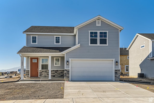 view of front of home featuring a porch, a garage, central air condition unit, and a mountain view