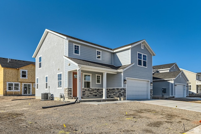 view of front of house featuring a garage, cooling unit, and a porch