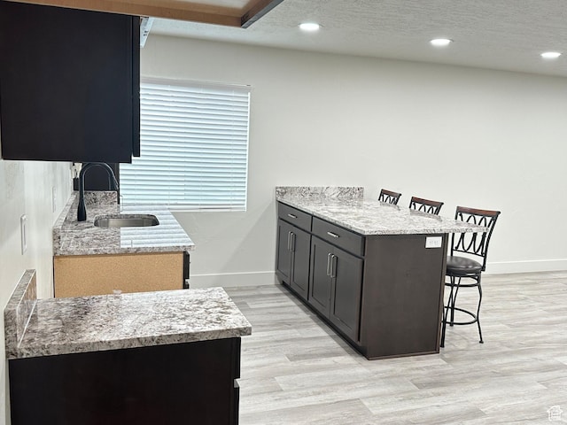 3 W 825 S, Willard, UT 84340 - kitchen featuring a kitchen breakfast bar, a sink, a peninsula, baseboards, and light wood-style flooring