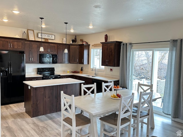 kitchen with dark brown cabinetry, a center island, light countertops, black appliances, and a sink