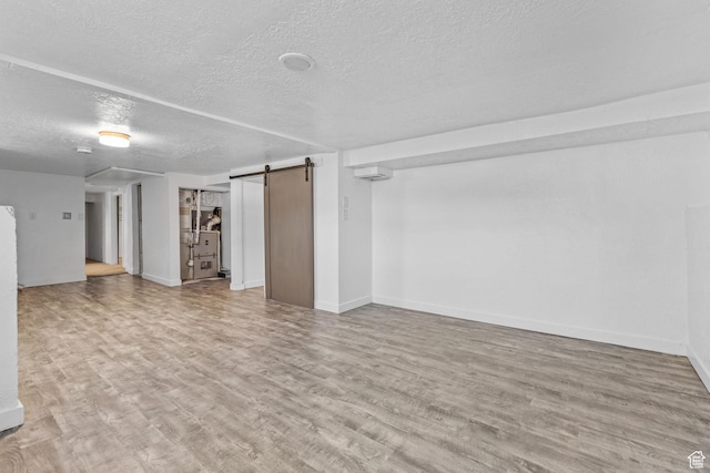 789 27th St, Ogden, UT 84403 - basement with a wall unit AC, a barn door, a textured ceiling, and light hardwood / wood-style flooring